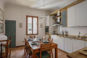 una cucina con tavolo e sedie e una cucina con armadietti bianchi di Charming Apartment in Oltrarno a Firenze