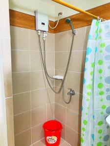 a shower with a red bucket in a bathroom at Cozynest Condotel Baguio in Baguio