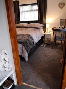 um quarto com uma cama, uma janela e uma cadeira em Kippford Stables em Kippford