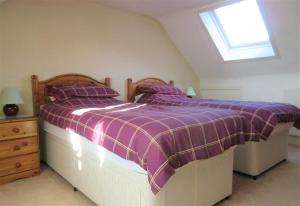 a bedroom with a purple and white bed with a window at Ailsa Cottage in Newton Stewart