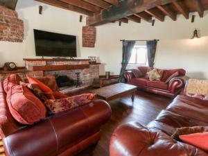 a living room with leather furniture and a fireplace at Windmill On The Farm in Ormskirk