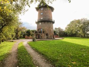 a brick tower in a field with a dirt road at Windmill On The Farm in Ormskirk