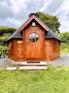 a small wooden cabin with a door in the grass at Cruachan Caravan and Camping Farm in Killin
