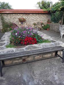 a bench in front of a garden with flowers at СТАИ ЗА ГОСТИ ПОДКОВА in Shabla