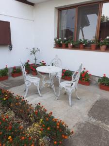 two white chairs and a table in a patio with flowers at СТАИ ЗА ГОСТИ ПОДКОВА in Shabla