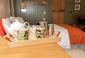 a tray filled with tea pots and mugs on a bed at The Hide at Woodside in St. Andrews