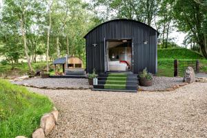 einen schwarzen Schuppen mit einem Bett und einem Pavillon in der Unterkunft The Hide at Woodside in St Andrews