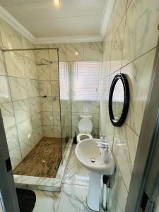 a bathroom with a toilet and a sink and a shower at The Pool_deck apartment in Lebowakgomo