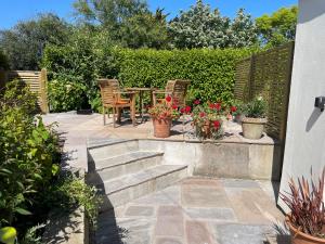 un patio con mesa, sillas y flores en Meadowside, en Saint Mawes