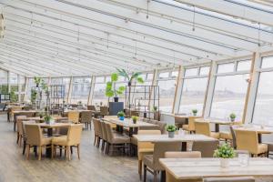 a restaurant with tables and chairs and windows at De Pier Suites in Scheveningen