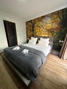 a bedroom with a large bed with a painting on the wall at Hotel NOA Kazbegi in Stepantsminda