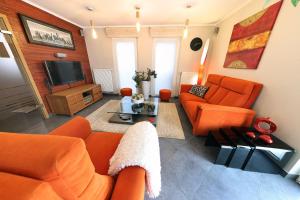 d'un salon doté d'un mobilier orange et d'une télévision. dans l'établissement ONSEN PLACE by Ardenne Places, à Spa