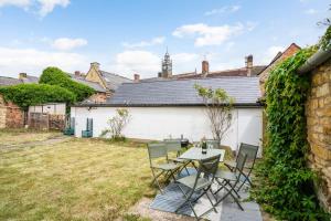a patio with a table and chairs in a yard at Moreton High Street - Sleeps 10, with private garden in Moreton in Marsh