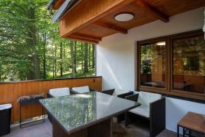 a screened in porch with a glass table and chairs at Wellness chata Chalet de Glatz in Komorní Lhotka