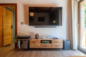 a living room with a wooden dresser with a television on the wall at Wellness chata Chalet de Glatz in Komorní Lhotka