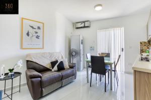 uma sala de estar com um sofá e uma mesa em Spacious, 1BR duplex off UNI/Hospital with WIFI by 360 Estates em Msida