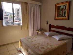 ein Schlafzimmer mit einem Bett und einem großen Fenster in der Unterkunft Colle Tourist Hotel in Criciúma