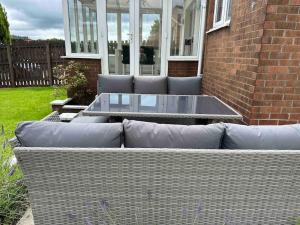 eine Korbcouch, die vor einem Haus sitzt in der Unterkunft Family friendly detached 2 bed home, Loch Lomond in Bonhill