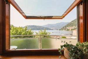 a window with a view of the water and mountains at Piazza Cavour Lake View - by MyHomeInComo in Como