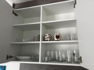 a white cabinet filled with dishes and cups at Helle Ferienwohnung Waldblick mit Balkon und Garten in Hatten +16 photos