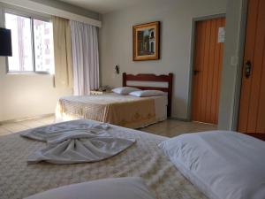 a hotel room with two beds and a window at Colle Tourist Hotel in Criciúma