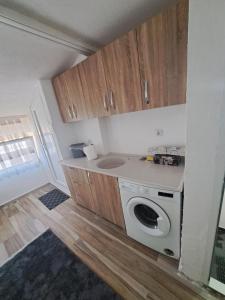 une petite cuisine avec un lave-linge et des placards en bois dans l'établissement Arel's Home, à Prizren