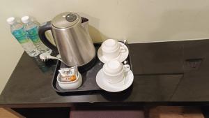 バヤンレパスにあるザ コルム ビュー ホテルのお茶ポット、黒いテーブルのカップ