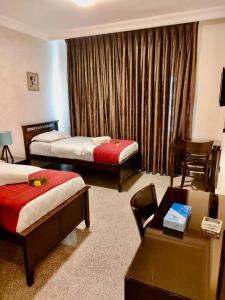 um quarto de hotel com duas camas e uma mesa em Tamrah Suites Hotel em Amã