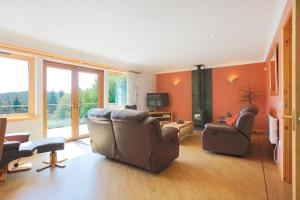 a living room with two leather chairs and a television at Honeysuckle, Colvend in Rockcliffe