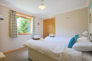 a bedroom with two beds and a window at Honeysuckle, Colvend in Rockcliffe