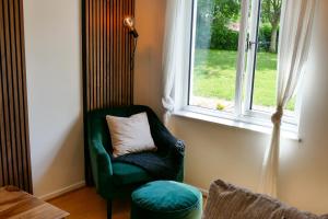 a green chair with a pillow in front of a window at Home in Longwell Green in Warmley