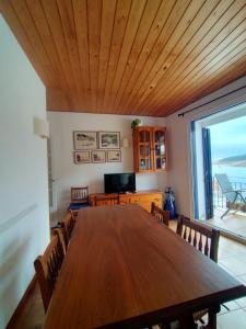 un comedor con una gran mesa de madera y una gran ventana en Patxei en Tamariu