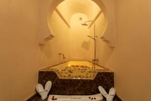 Palais Aix Kabaj &Spa في مراكش: حمام مع حوض مع طير على الحائط