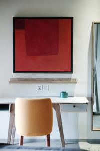 a desk with a chair and a painting on a wall at Kaia Gallery Hotel Hoi An in Hoi An
