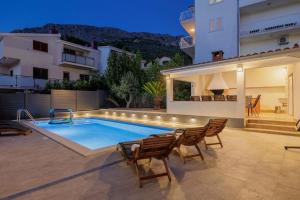 a swimming pool with chairs and a house at Villa Bella Split - Podstrana in Podstrana