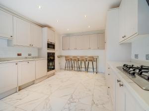 a white kitchen with white cabinets and bar stools at The Annexe At Moulton Grange in Brixworth