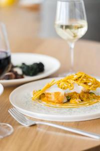 a plate of food on a table with a glass of wine at Fistral Beach Hotel and Spa - Adults Only in Newquay