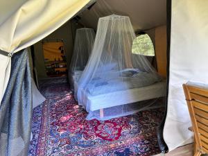 a bed in a tent with a mosquito net at Langø Feriecenter - Outdoor Lodge in Nakskov