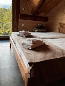 two towels on a bed in a room with a window at Brunarica Macesen Smogavc in Zreče