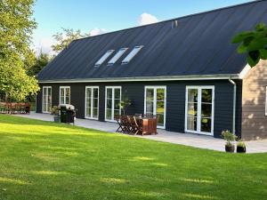 a house with a black roof and a patio at Langø Feriecenter - Garden View in Nakskov