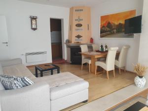 een woonkamer met een witte bank en een tafel bij Apartman Relax Čelebići in Konjic