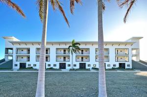 a large white building with palm trees in the foreground at Surf Ranch Resort - Popoyo in Popoyo