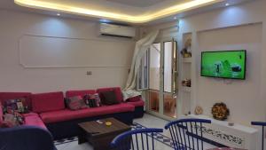 a living room with a red couch and a tv at المعمورة الشاطىء in Alexandria