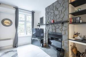 sala de estar con chimenea de piedra y TV en 155 Falaise - Forest Chalet in Old Village Mont Tremblant, en Mont-Tremblant