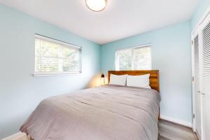 Schlafzimmer mit einem Bett mit blauen Wänden und Fenstern in der Unterkunft Coastal Charm in Gleneden Beach