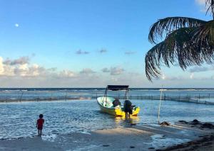 a child standing next to a boat on the beach at Casita Colibrí - An eco chic house in Mahahual