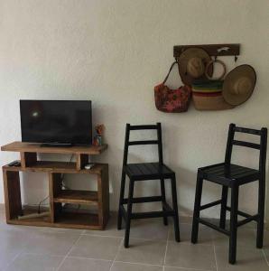 2 sillas y TV en una mesa con TV en Casita Colibrí - An eco chic house, en Mahahual