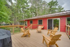 a deck with chairs and a red house at Beautiful Chetek Home with Prairie Lake Access! in Chetek