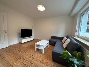 uma sala de estar com um sofá preto e uma televisão em Haus Nähe Hagenbecks Tierpark em Hamburgo