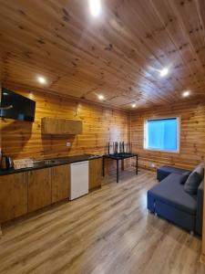 sala de estar con paredes de madera y sofá azul en Domki Róża Bobolin en Bobolin